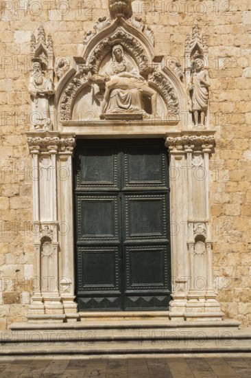 Ornate dark green entrance door decorated with carved religious figures at Franciscan Monastery,