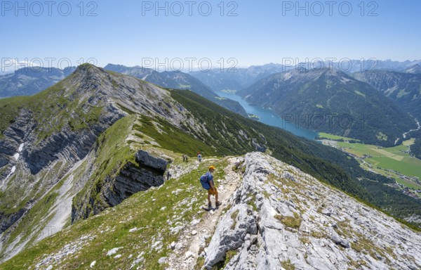 Mountaineer on the hiking trail on the summit ridge of the Unnütz, behind Achensee and summit of