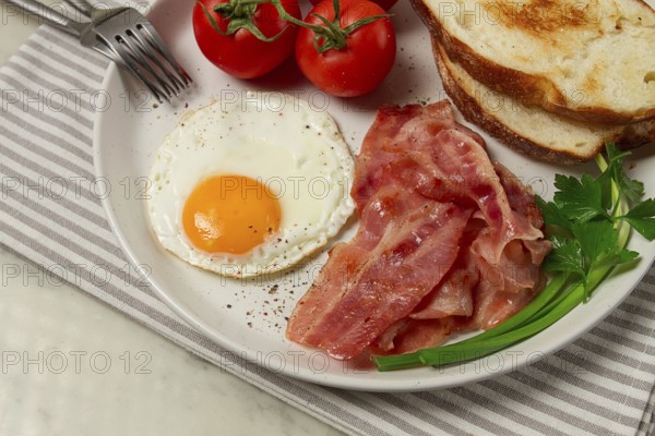 Breakfast, fried egg, bacon and bread, with cherry, on a light background, homemade, no people