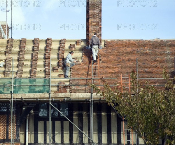 Men re-roofing historic building with clay tiles, Thorpeness, Suffolk, England, United Kingdom,