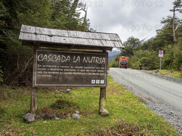Information board at waterfall Cascada La Nutria, overlander truck on gravel road, Valle