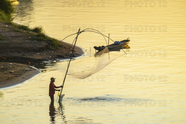 Fisherman with a sinking net at sunset on the Mekong, Luang Prabang, Laos, Asia