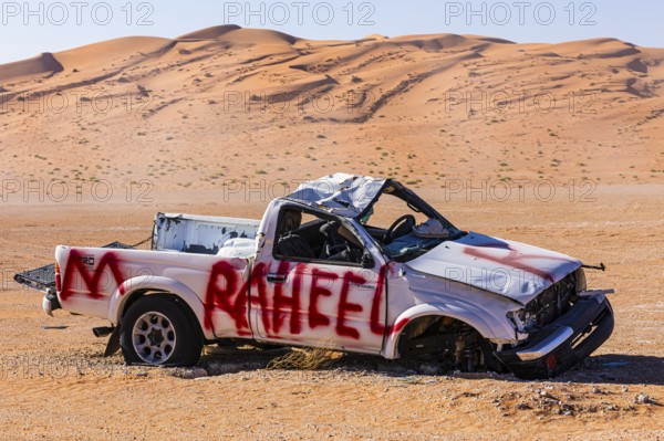 Car wreck, left behind in the Rub al Khali desert, sand dunes sculpted by the wind, Dhofar