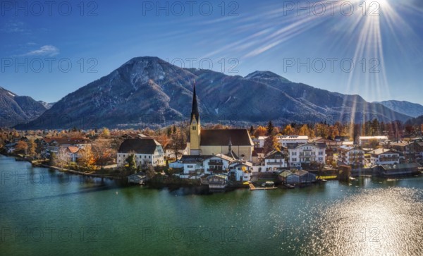 A picturesque lakeside village in an autumn landscape, surrounded by mountains and under a bright