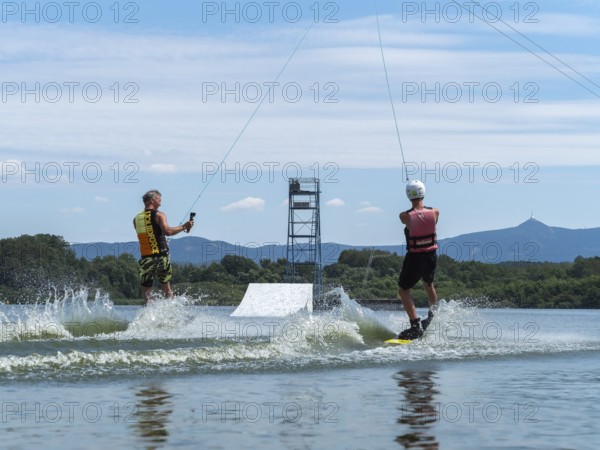 Water sports with wakeboard, two men riding side by side in the lake, camera in hand, water skiing
