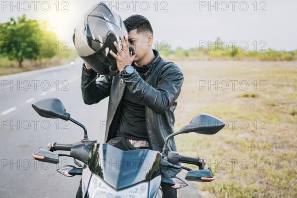 Male biker on motorcycle putting on safety helmet. Biker motorcycle safety concept, Young