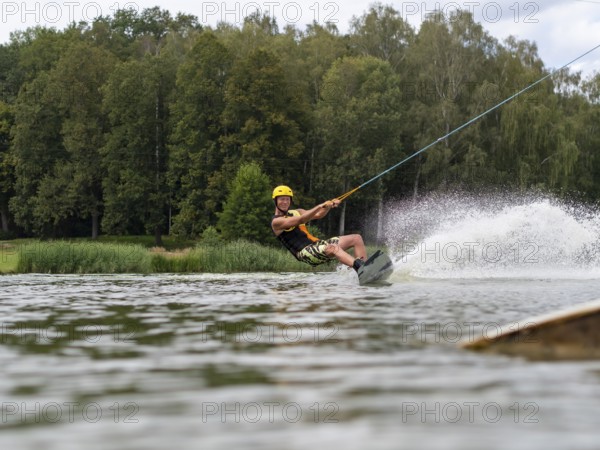 Sporty man with wakeboard, water sports, water skiing and wake park