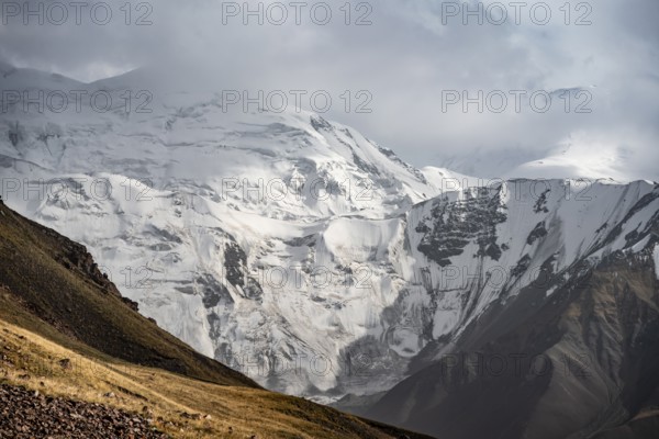 Dramatic mountain landscape, mountain valley, behind glaciated and snow-covered mountain peak Pik