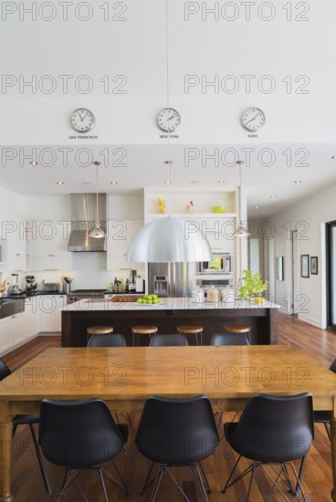 Open-concept dining and kitchen area with antique dining table with black leather and plastic