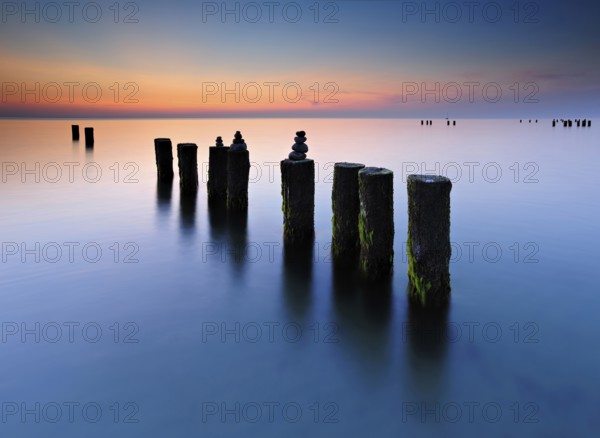 Stone pyramids on old groynes with algae in the water on the beach of the Baltic Sea, long exposure