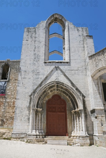 A Gothic church ruin with ornate archways standing out against the clear blue sky, Convento do