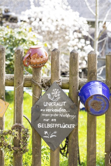 Picket fence decorated with various pots and buckets and mindful verse about the rain, Altendorf,