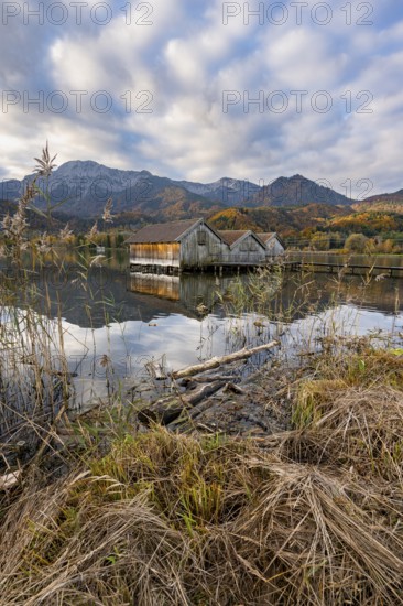 Boathouses in the lake at sunrise, Lake Kochel in autumn with reflection, behind mountain peaks