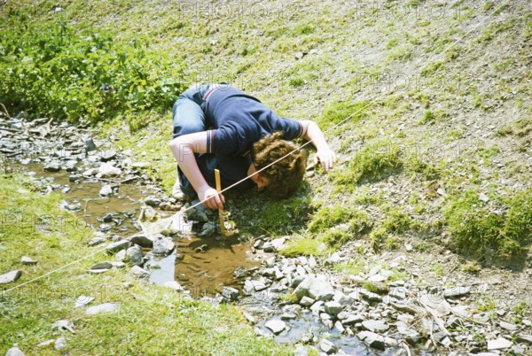 Secondary school student doing geographical fieldwork, Great Britain 1970s: Girl measuring the