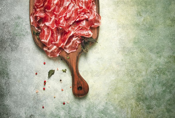 Prosciutto on a cutting board, top view, appetizer, breakfast, spices and herbs