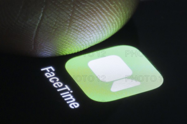 The Apple FaceTime app can be seen on a smartphone next to a finger. Berlin, 27.03.2024