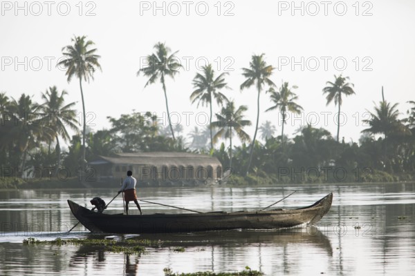 Fisherman in the morning with a boat on the Vembanad Lake, canal system of the backwaters, Kerala,