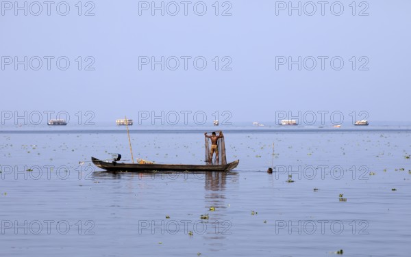 Fisherman on a small boat on the Vembanad Lake, canal system of the backwaters, Kerala, India, Asia