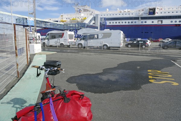 Several motorhomes are parked on a ferry car park, with a large ferry in the background, Transport,