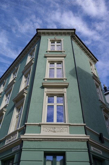 Historic building with mint facade and cream-coloured window frames under a clear blue sky with