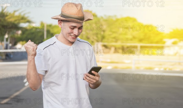 Man with winning gesture using cell phone in the street. Happy young man with winning gesture with