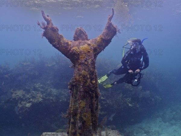 Diver with camera looking at an underwater statue of Jesus Christ (Christ of the Abyss), dive site