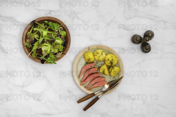 Top view of a rustic meal consisting of fresh green salad, hot smoked humpback salmon and boiled