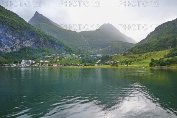 Mountainous landscape in a fjord reflecting the surrounding mountains and village, surrounded by