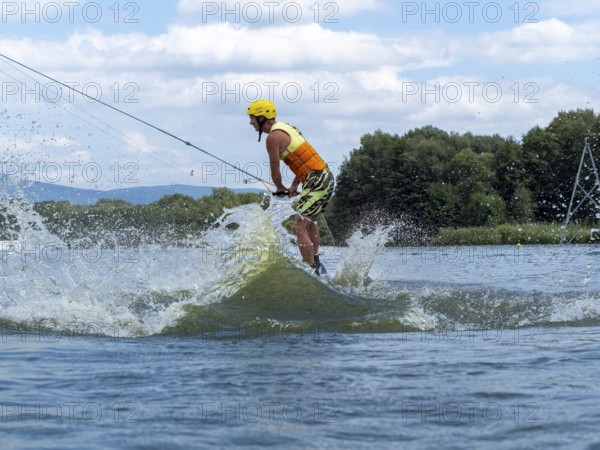 Sporty man with jump with wakeboard, water sports, water skiing and wake park