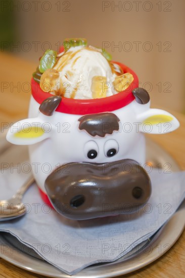 Ice cream in a cute cow cup with pieces of fruit, served on a table, autumn creations, Cafe Kuh,