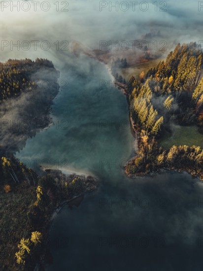 Autumn sunrise in the foothills of the Alps with fog at Illasbergsee and Forggensee near Halblech