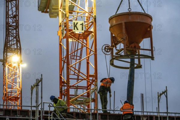 Concrete work, at dusk, on a large construction site building a residential and commercial complex,