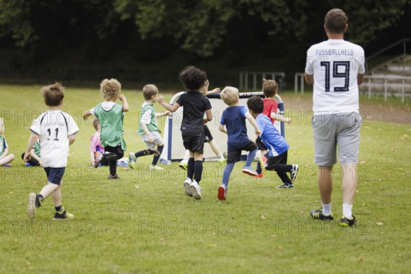 Volunteer coach trains children on the football pitch, Bonn, 19.06.2024