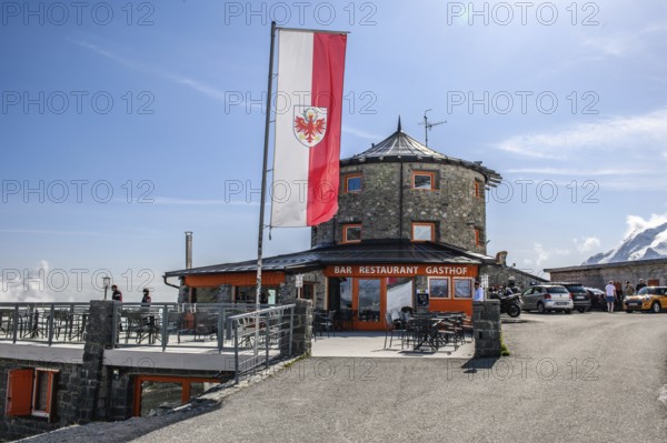 In front flag flag of South Tyrol behind it historic mountain hotel hotel restaurant bar inn alpine