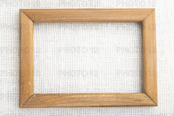 Wooden frame on smooth white linen tissue. Top view, flat lay, natural textile background and