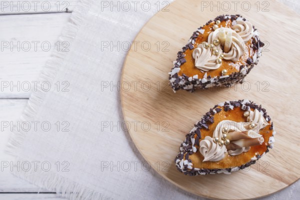 Cakes with chocolate chips and cream decorations on wooden board on white background. selective