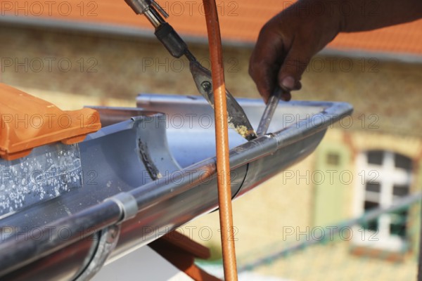 Roofer doing tinsmith work on a gutter