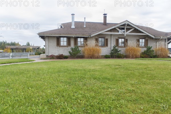 Modern wooden cottage with green lawn and landscape design with ornamental grasses and pines