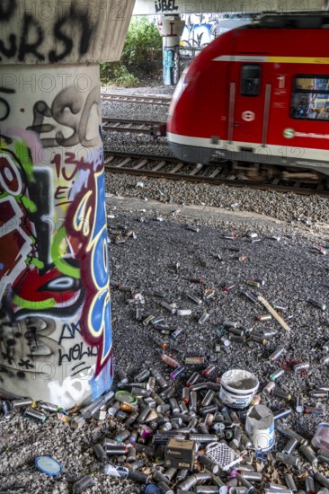 Empty spray paint cans, on a railway line below a road bridge, thrown away, disposed of by the