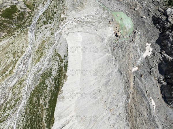 Stream flowing from a glacial lake breaks through a large moraine, valley Val Ferret, aerial view,