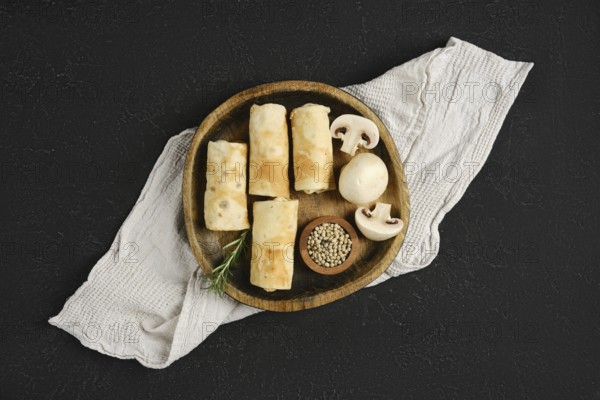 Thin pancakes stuffed with mushrooms on a wooden plate. The rustic setting enhances the appetizing