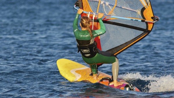 Woman in green wetsuit windsurfing on a yellow surfboard, windsurfer, Meltemi windsurfing spot,