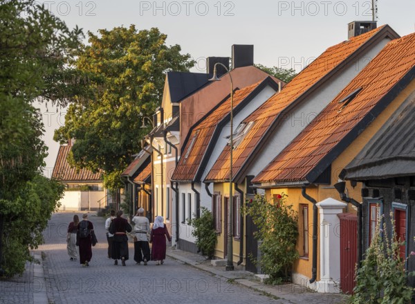 Visitors to the Medieval Week walk along a cobbled street in medieval dress, old houses, former