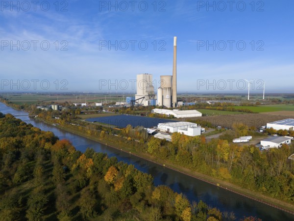A coal-fired power plant in a rural landscape, with wind turbines and a canal along colourful