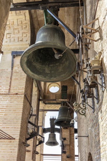 Close-up of an ancient bell tower with massive bells and metal structures, Seville