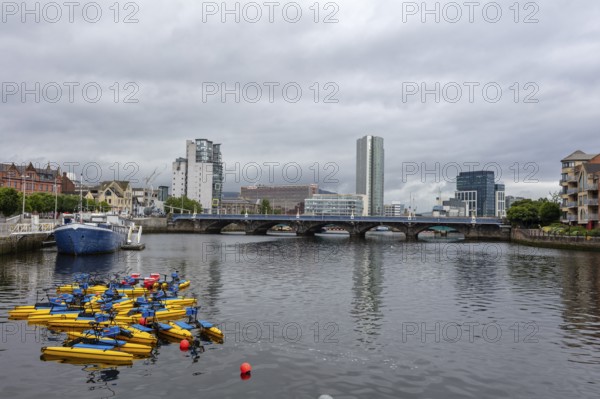City view with skyscrapers and bridge over a river on which boats are floating, Belfast