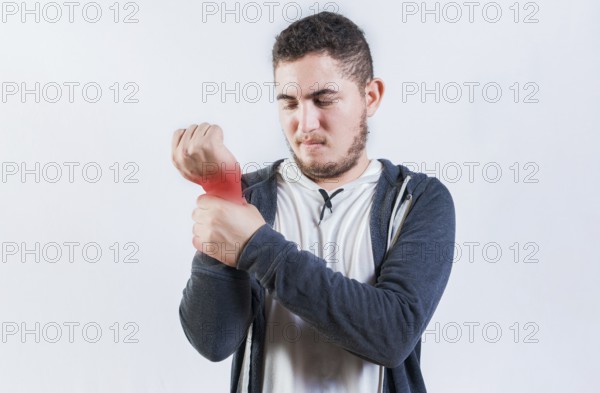 Suffering young man with pain in hand joints isolated. Person with arthritis pain rubbing hand