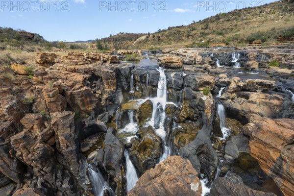 Waterfalls between orange-coloured rocks on the Treur River, Bourke's Luck Potholes, long exposure,