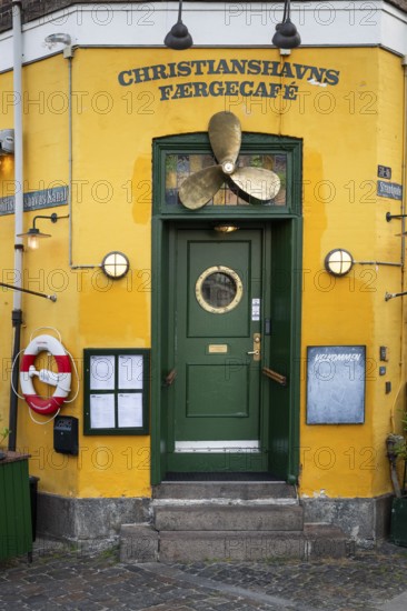 Green entrance door with ship's propeller, yellow painted façade, Christianshavns Færgecafé,