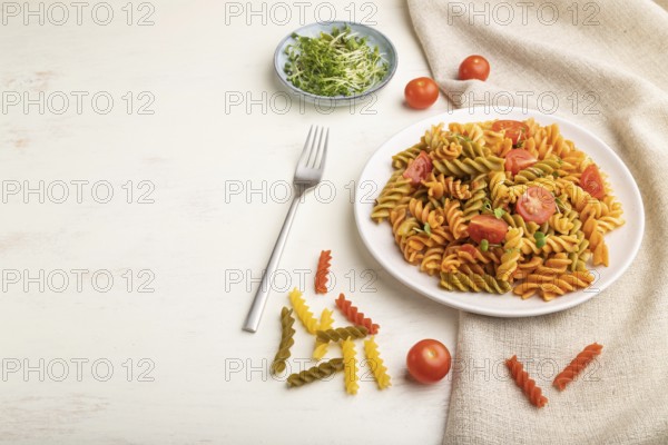 Tortiglioni semolina pasta with tomato and microgreen sprouts on a white wooden background and